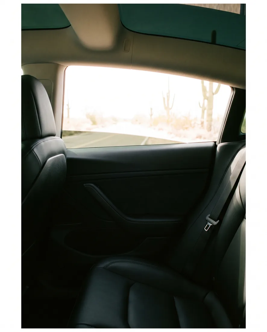 View from inside a car looking out through tinted glass at a sunlit desert road